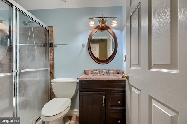 bathroom featuring vanity, a shower with shower door, and toilet