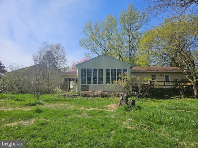 rear view of house featuring a wooden deck and a yard