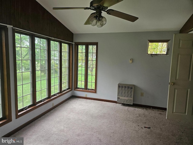 carpeted spare room featuring vaulted ceiling, heating unit, and ceiling fan