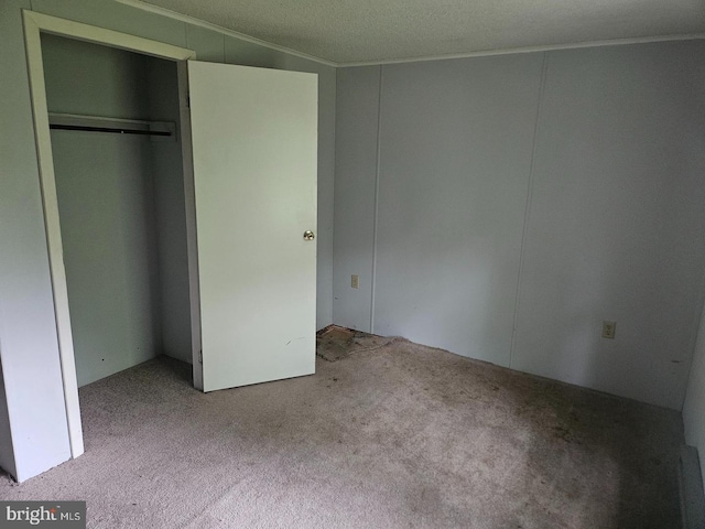 unfurnished bedroom with ornamental molding, light colored carpet, and a closet