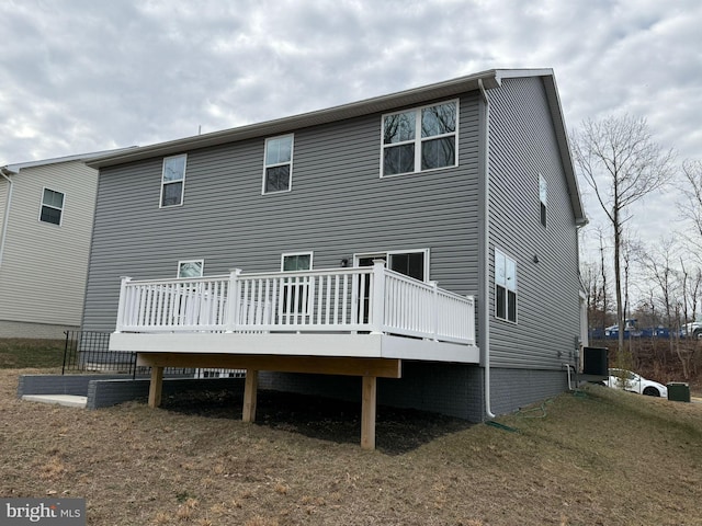 back of property with a wooden deck, central AC unit, and a lawn