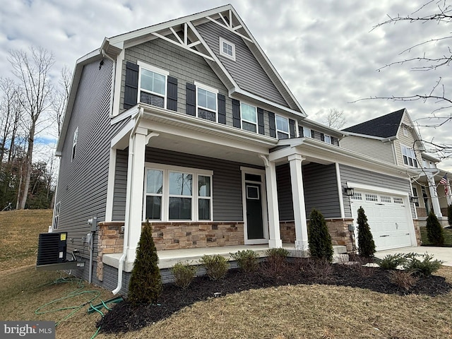 craftsman-style house with a garage, a front lawn, covered porch, and central air condition unit