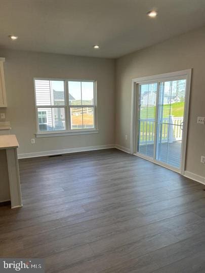 unfurnished living room featuring plenty of natural light and dark hardwood / wood-style flooring