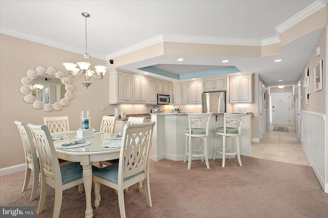 carpeted dining space featuring ornamental molding, a raised ceiling, and a chandelier