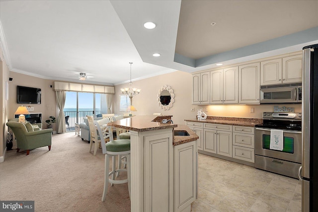 kitchen featuring sink, a center island, appliances with stainless steel finishes, pendant lighting, and cream cabinets