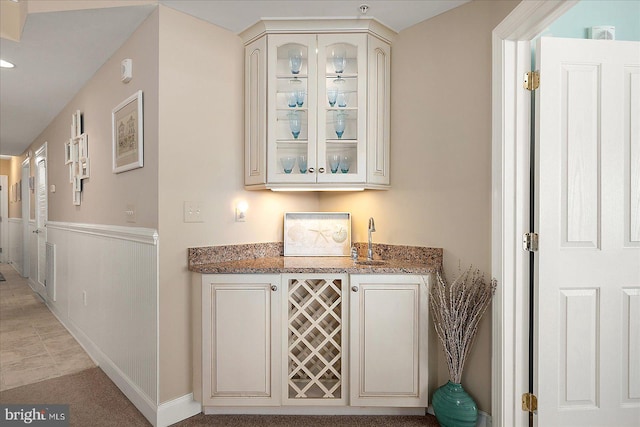 bar with light stone countertops and cream cabinets