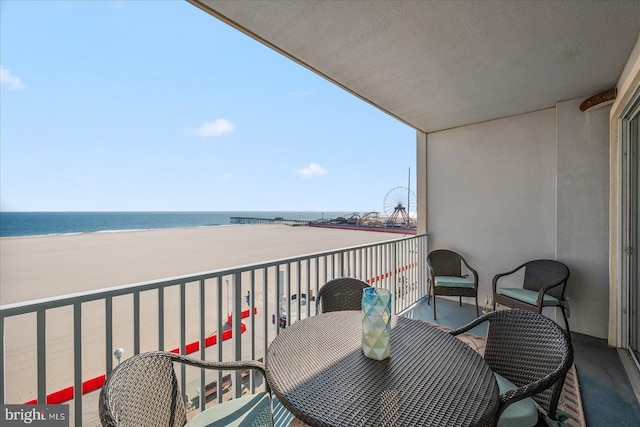 balcony with a water view and a view of the beach