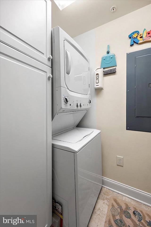 clothes washing area featuring cabinets, stacked washer / drying machine, and electric panel