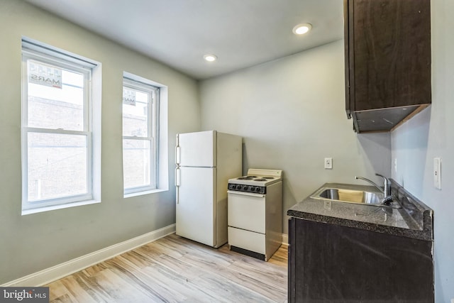 kitchen with sink, white appliances, dark brown cabinets, and light wood-type flooring