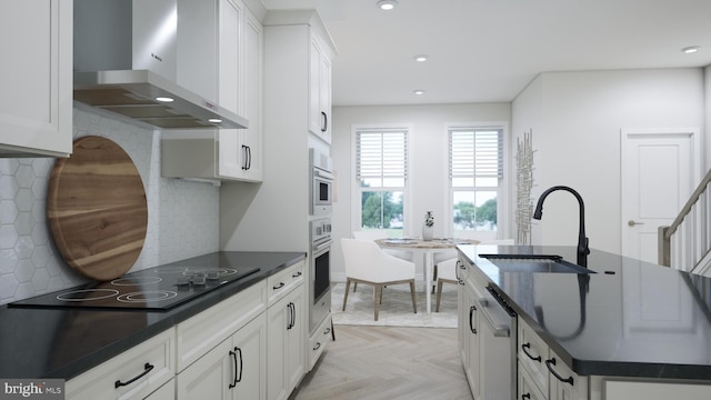 kitchen with sink, white cabinets, light parquet floors, stainless steel appliances, and wall chimney exhaust hood