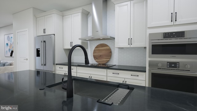 kitchen featuring appliances with stainless steel finishes, white cabinets, backsplash, and wall chimney exhaust hood