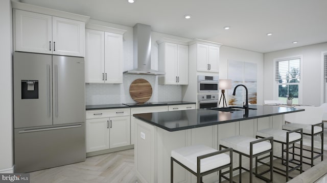 kitchen with wall chimney exhaust hood, stainless steel appliances, a breakfast bar, and sink