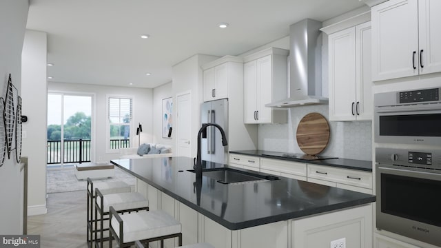 kitchen featuring wall chimney exhaust hood, white cabinetry, a kitchen breakfast bar, stainless steel double oven, and light parquet flooring