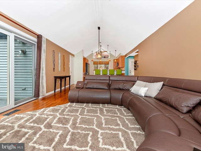 living room featuring lofted ceiling, a notable chandelier, and wood-type flooring