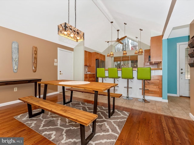 dining area featuring high vaulted ceiling and light hardwood / wood-style floors