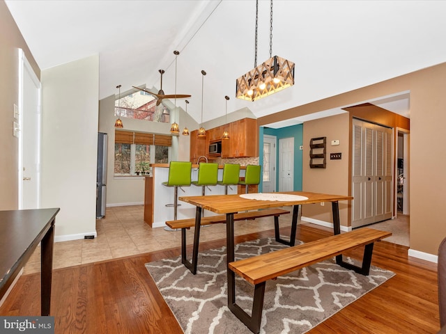 dining space with light hardwood / wood-style flooring and high vaulted ceiling