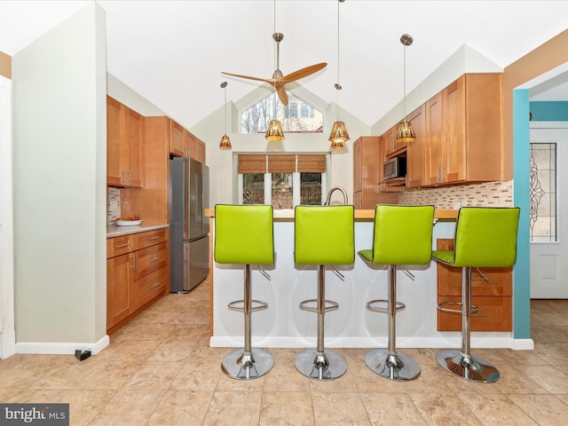 kitchen with hanging light fixtures, vaulted ceiling, a breakfast bar, and appliances with stainless steel finishes