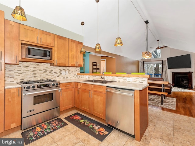 kitchen with sink, hanging light fixtures, appliances with stainless steel finishes, kitchen peninsula, and decorative backsplash