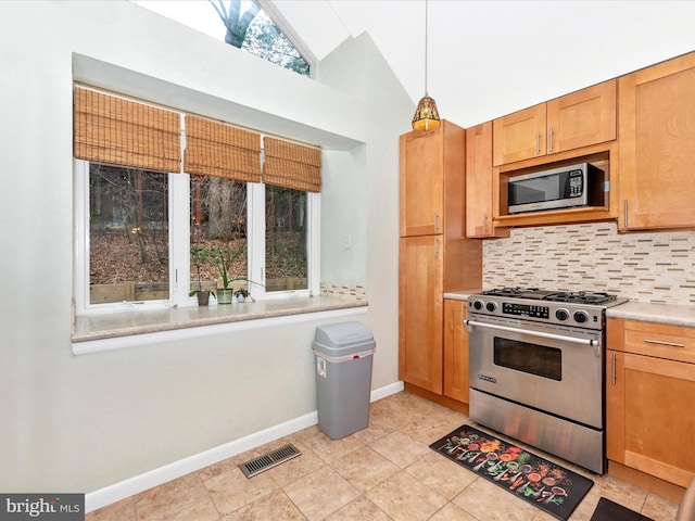 kitchen featuring light tile patterned flooring, decorative light fixtures, lofted ceiling, backsplash, and stainless steel appliances