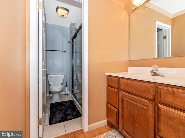 bathroom featuring crown molding, hardwood / wood-style flooring, a shower with door, vanity, and toilet