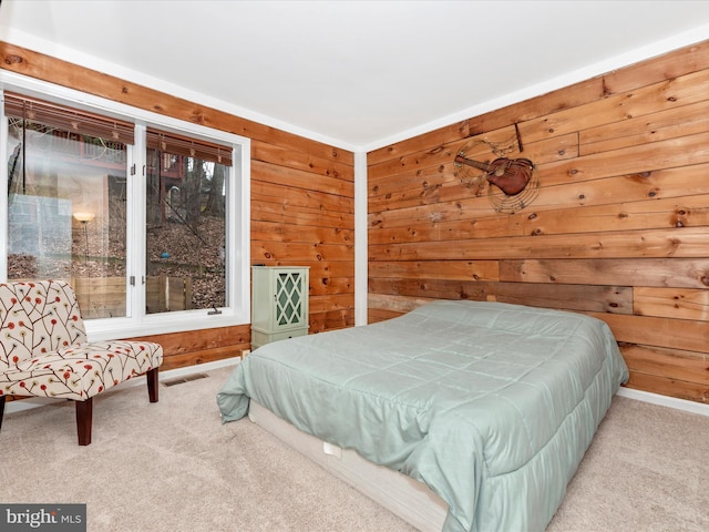 bedroom with wooden walls and light carpet