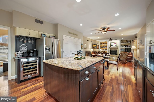 kitchen with wine cooler, dark hardwood / wood-style flooring, dark brown cabinetry, and a center island