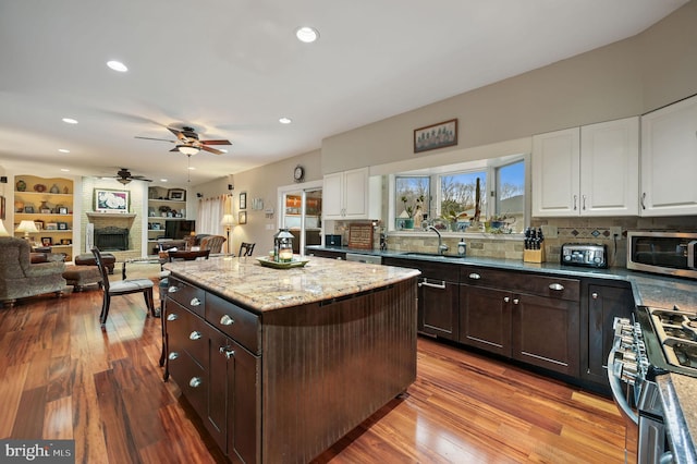 kitchen featuring sink, stainless steel appliances, dark brown cabinetry, a fireplace, and white cabinets