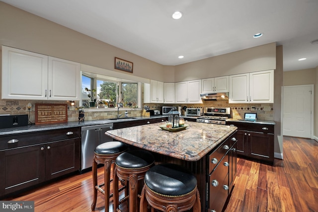 kitchen featuring sink, dark brown cabinets, dark hardwood / wood-style floors, a kitchen island, and stainless steel appliances