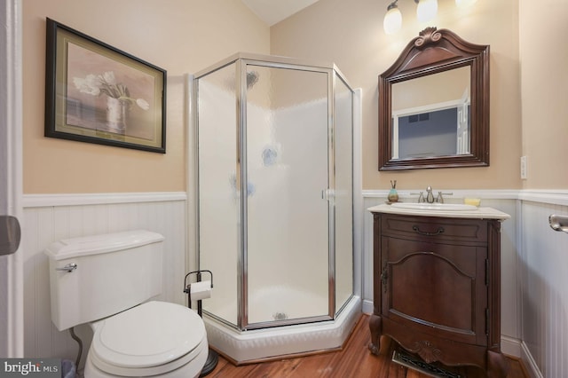 bathroom featuring vanity, wood-type flooring, toilet, and walk in shower