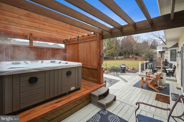 deck featuring a hot tub, grilling area, and a pergola