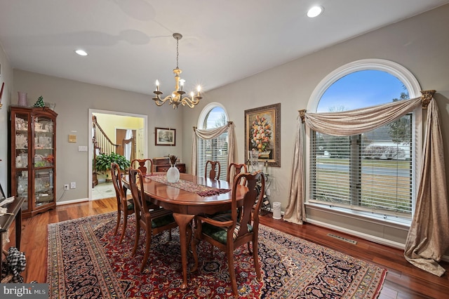 dining space with a healthy amount of sunlight, a notable chandelier, and dark hardwood / wood-style flooring