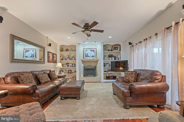 living room with built in shelves, ceiling fan, and a fireplace