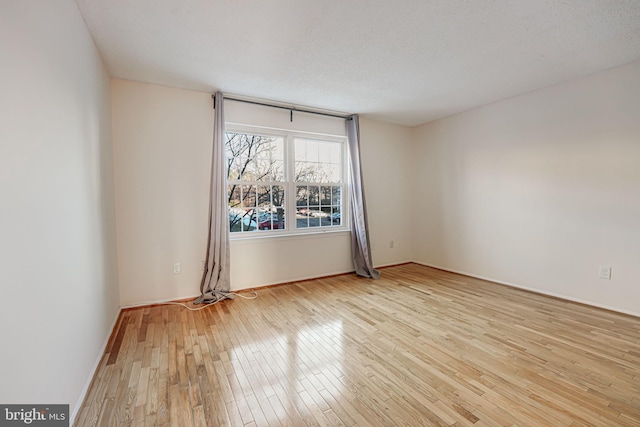 spare room featuring light hardwood / wood-style floors and a textured ceiling