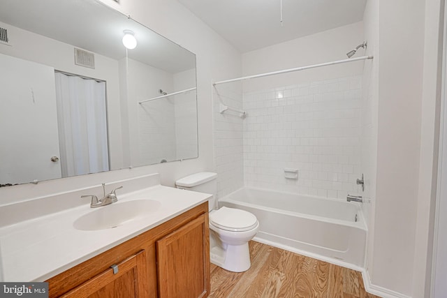 full bathroom featuring wood-type flooring, toilet, tiled shower / bath combo, and vanity