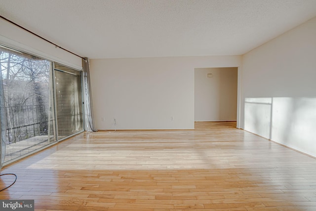 unfurnished room with a textured ceiling and light wood-type flooring