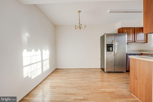 kitchen with pendant lighting, stainless steel appliances, a chandelier, and light wood-type flooring