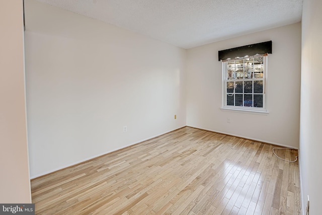 spare room featuring a textured ceiling and light hardwood / wood-style floors