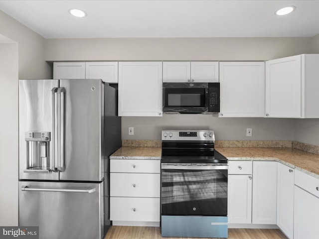 kitchen featuring stainless steel appliances, white cabinets, light stone counters, and light hardwood / wood-style floors