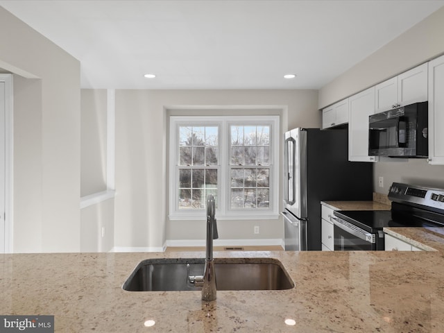 kitchen featuring white cabinetry, appliances with stainless steel finishes, light stone countertops, and sink