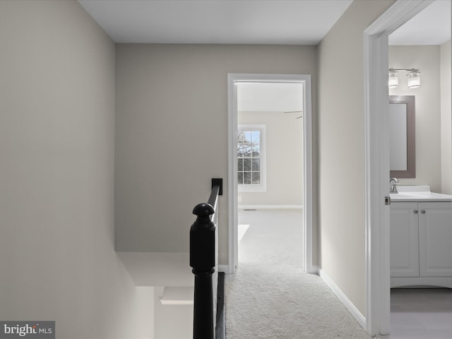 hallway with sink and light colored carpet