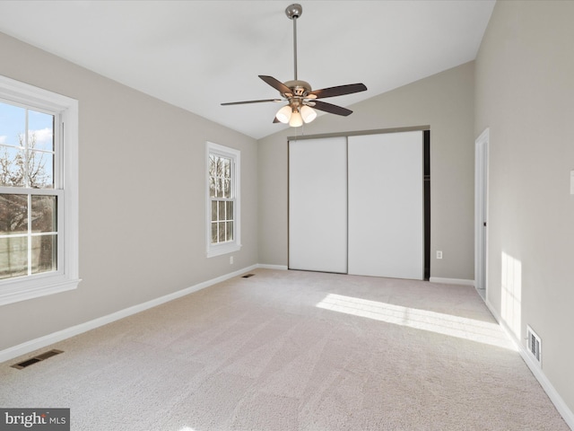 unfurnished bedroom featuring ceiling fan, a closet, lofted ceiling, and light carpet