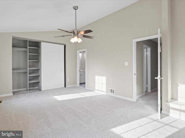 unfurnished bedroom with ensuite bath, light colored carpet, vaulted ceiling, a closet, and ceiling fan