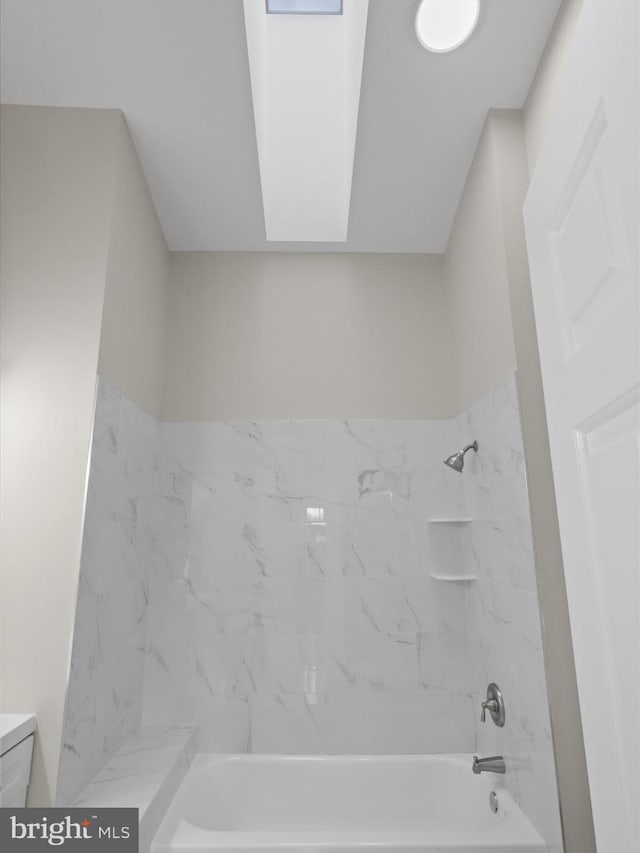 bathroom featuring vanity, tiled shower / bath combo, and vaulted ceiling