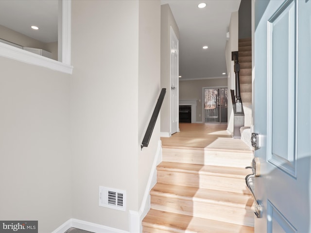 stairs featuring crown molding and wood-type flooring