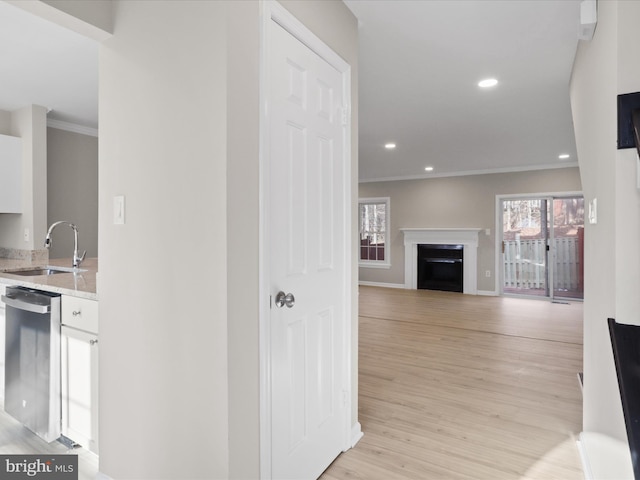 corridor with ornamental molding, sink, and light wood-type flooring