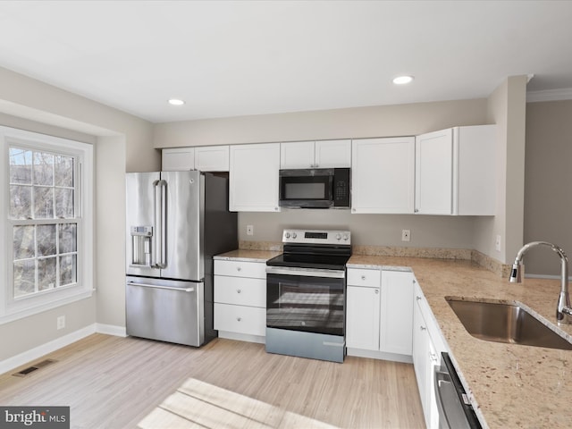 kitchen featuring stainless steel appliances, white cabinetry, sink, and light stone counters