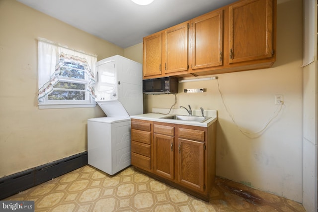 clothes washing area with baseboard heating, cabinets, stacked washer / dryer, and sink