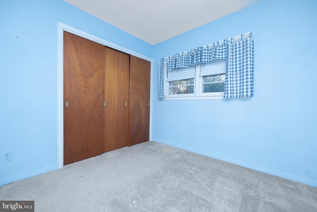 unfurnished bedroom featuring light colored carpet and a closet