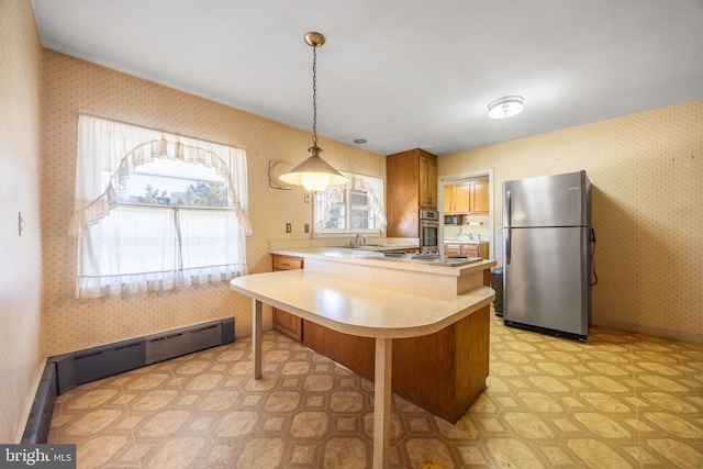 kitchen with sink, stainless steel refrigerator, hanging light fixtures, a kitchen breakfast bar, and kitchen peninsula