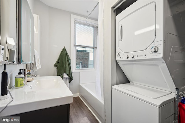 laundry area featuring stacked washer and dryer, sink, and dark hardwood / wood-style flooring